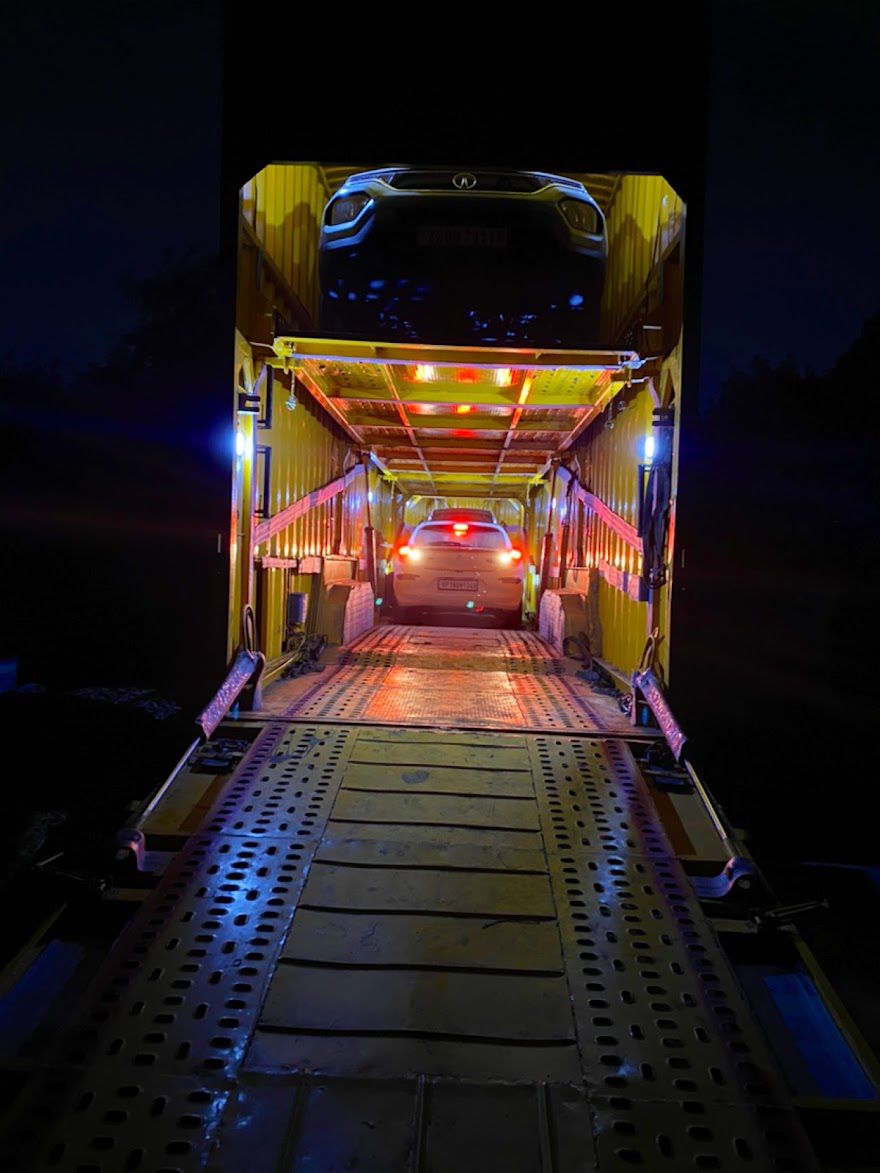 Car safely loaded inside container carrier at night for long-distance transport